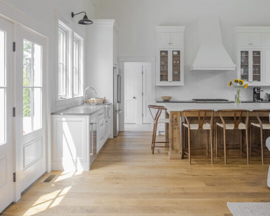 bright white kitchen with wood island and matching dark wide plank flooring