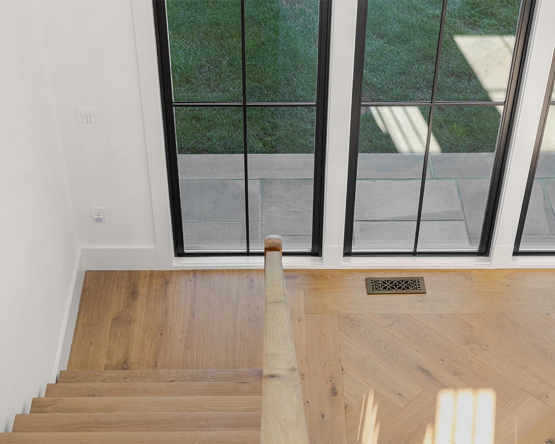 Staircase with color coordinated treads, clean lines juxtaposed with herringbone designed wood floor