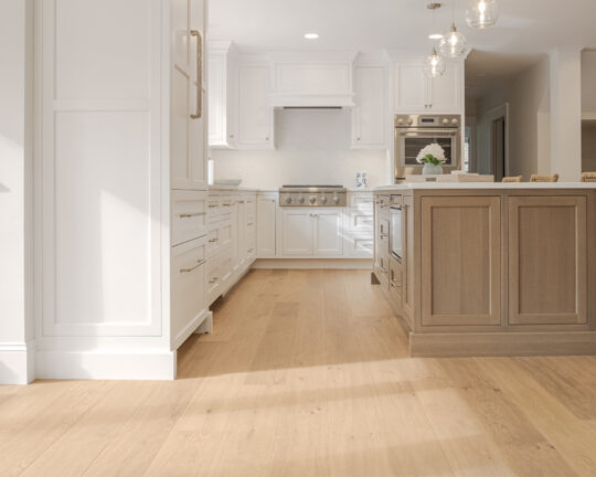 white kitchen cabinets walls and countertops with a wood island and natural light wide plank floors