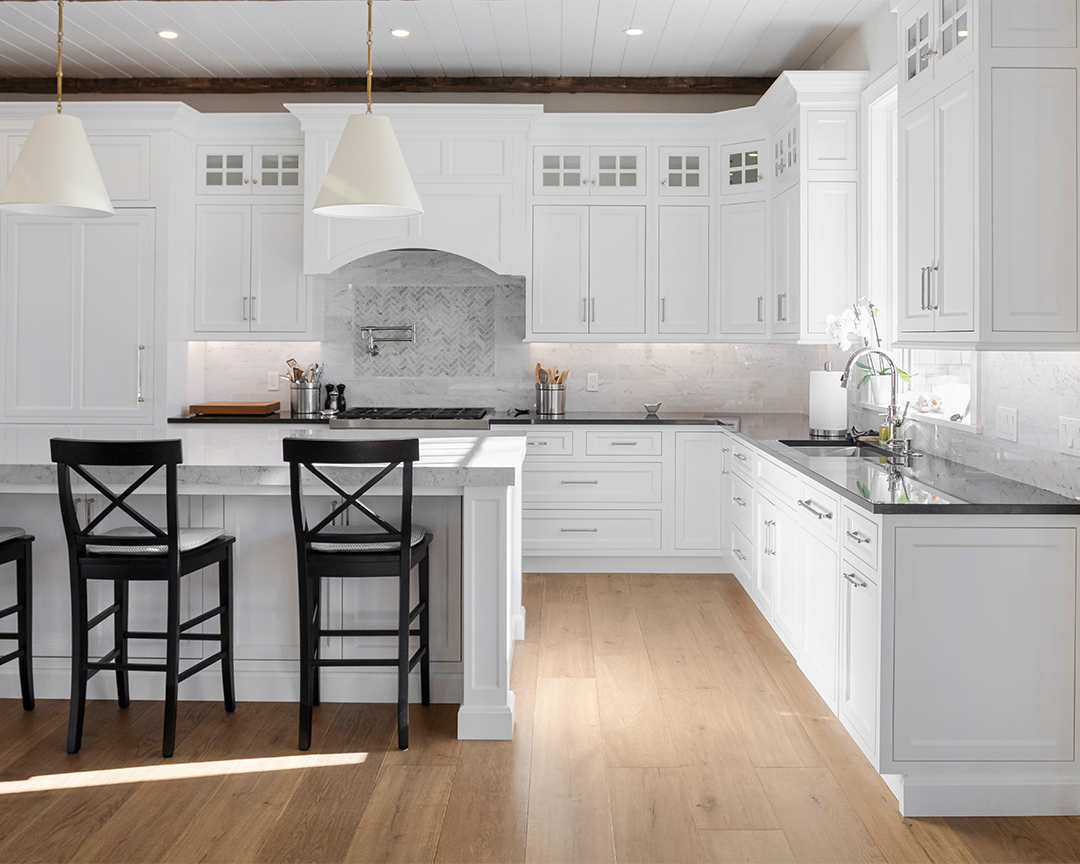bright white kitchen with black countertops and beautiful natural looking wide oak floors