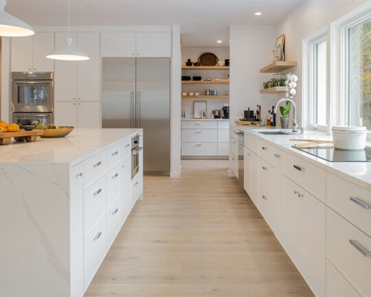 Bright white kitchen with white cabinets, exposed shelves, and wide plank floors