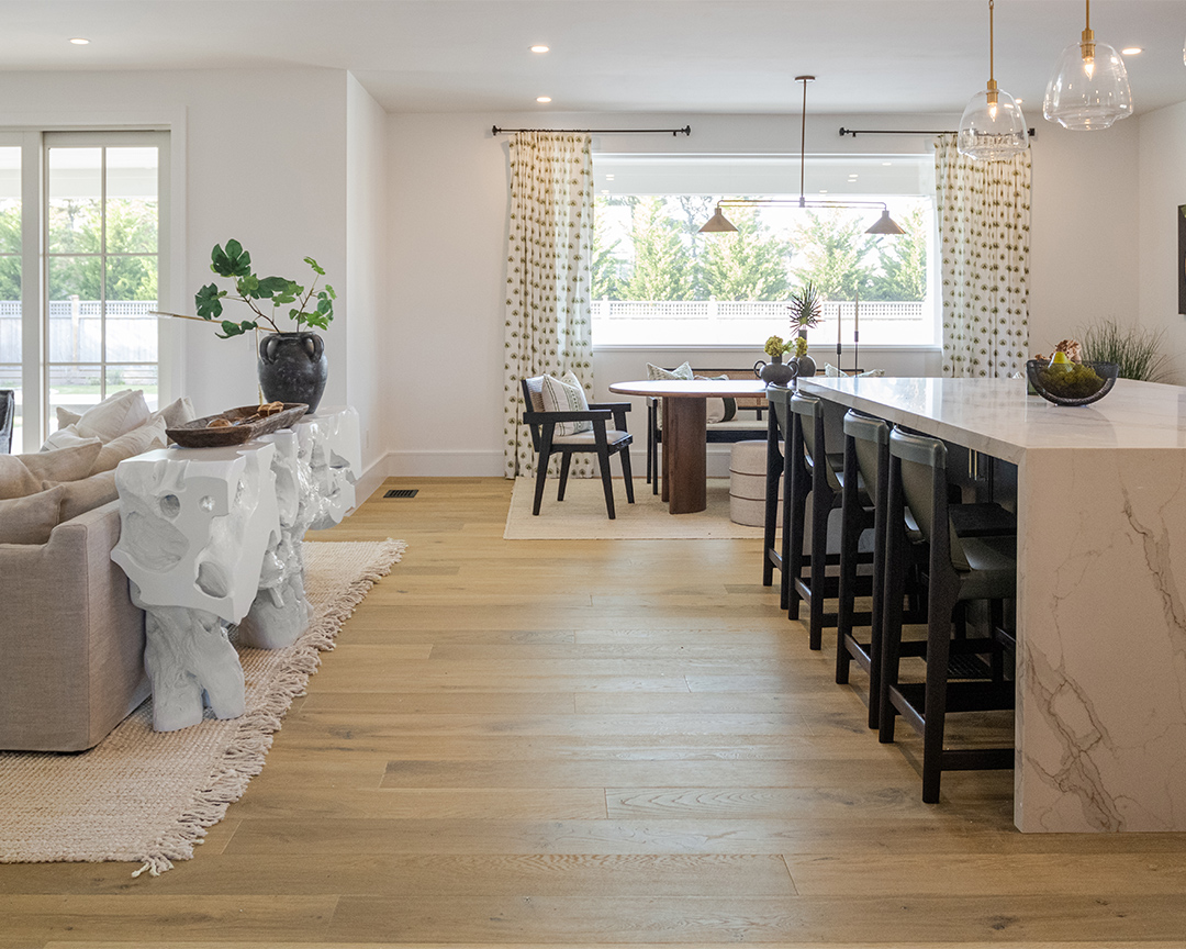 Bright and open dining space and living room with decorative accents and wide plank wood flooring