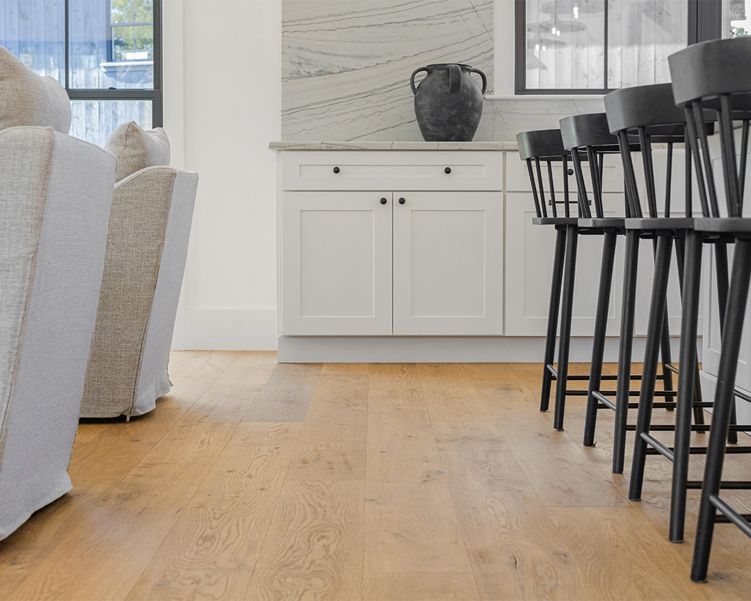 Close up of rustic wood floor and dining area with chairs and white cabinets
