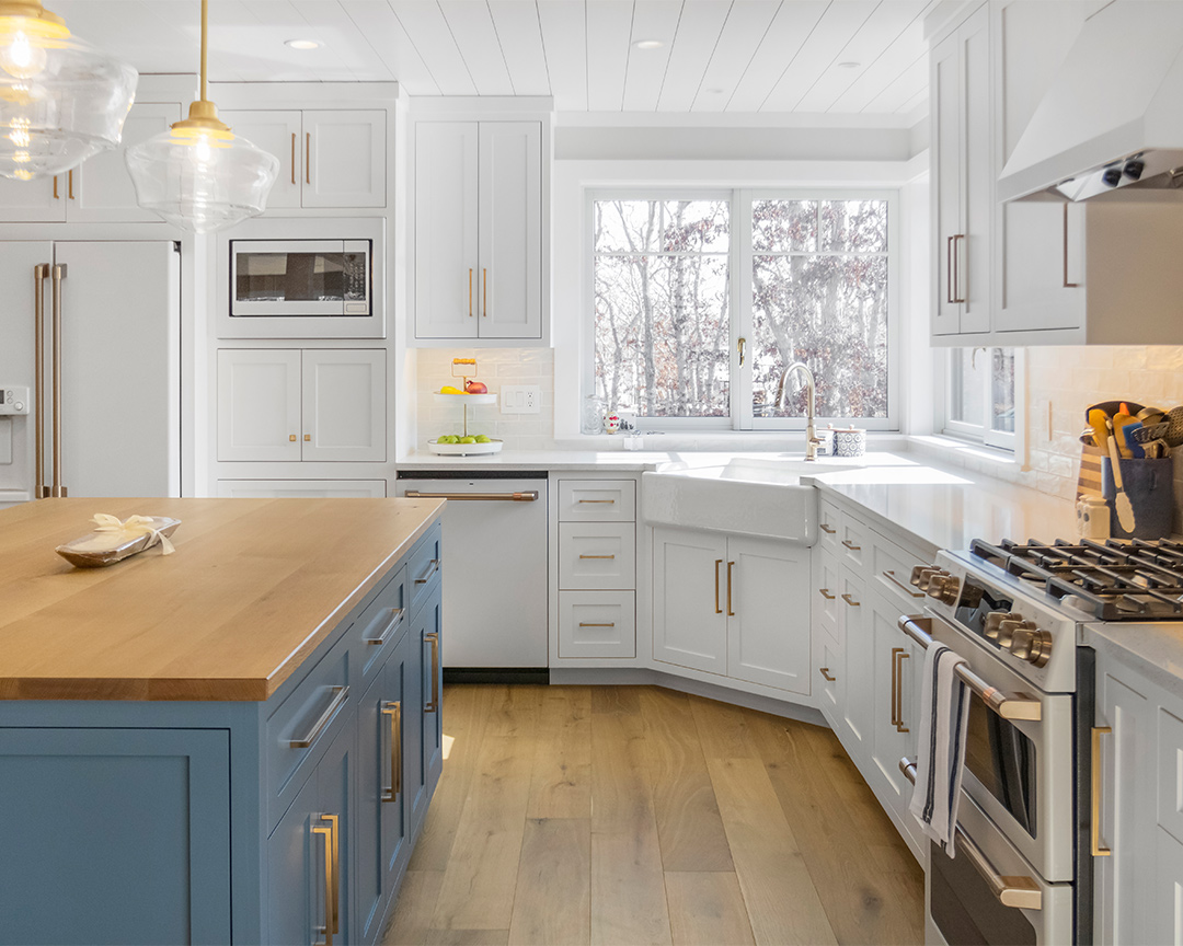 Kitchen with rounded wall and blue island with an oak wood floor