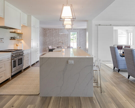 Light beige wood flooring in a modern kitchen with white cabinets and textured island