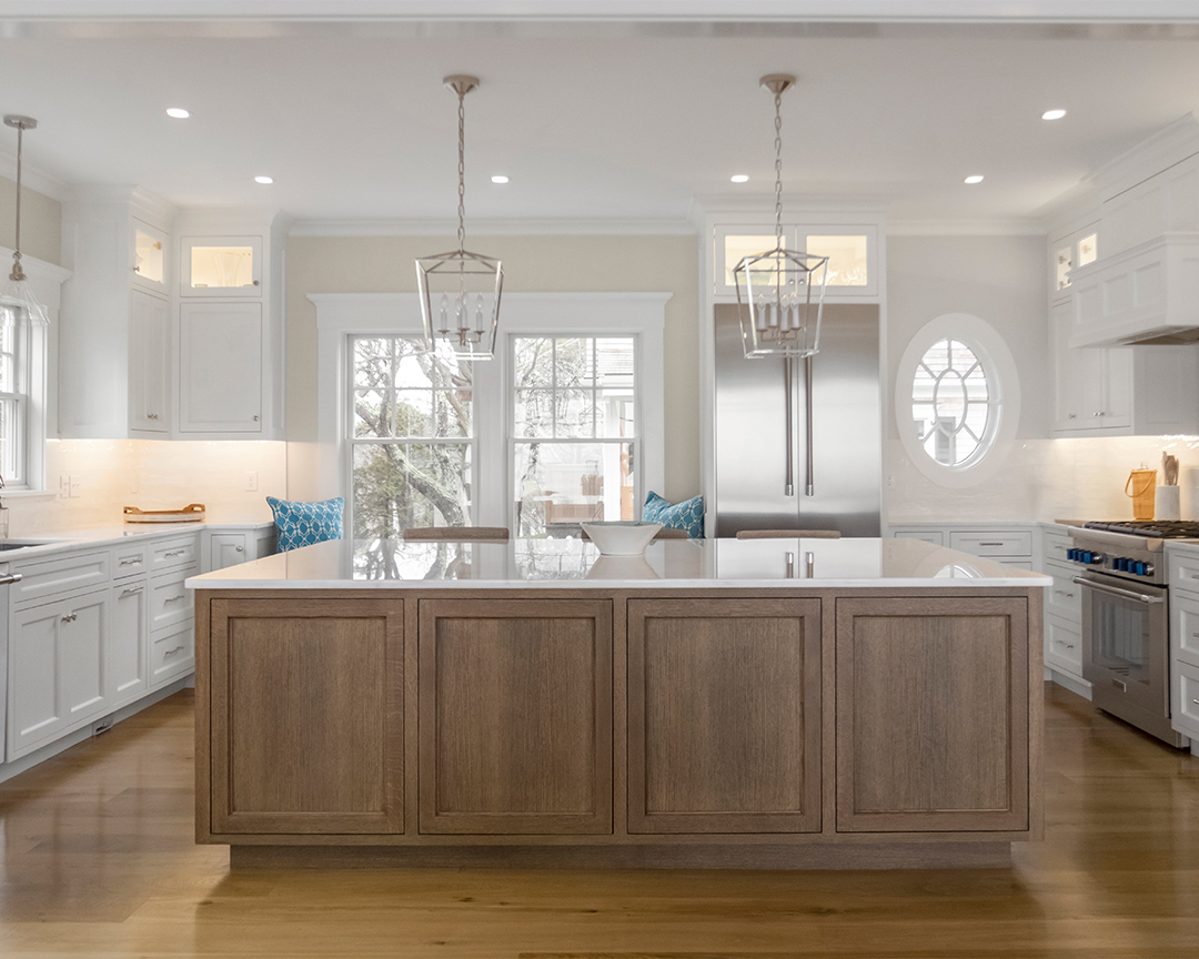 bright kitchen with large wood island white counter tops and natural wide plank flooring