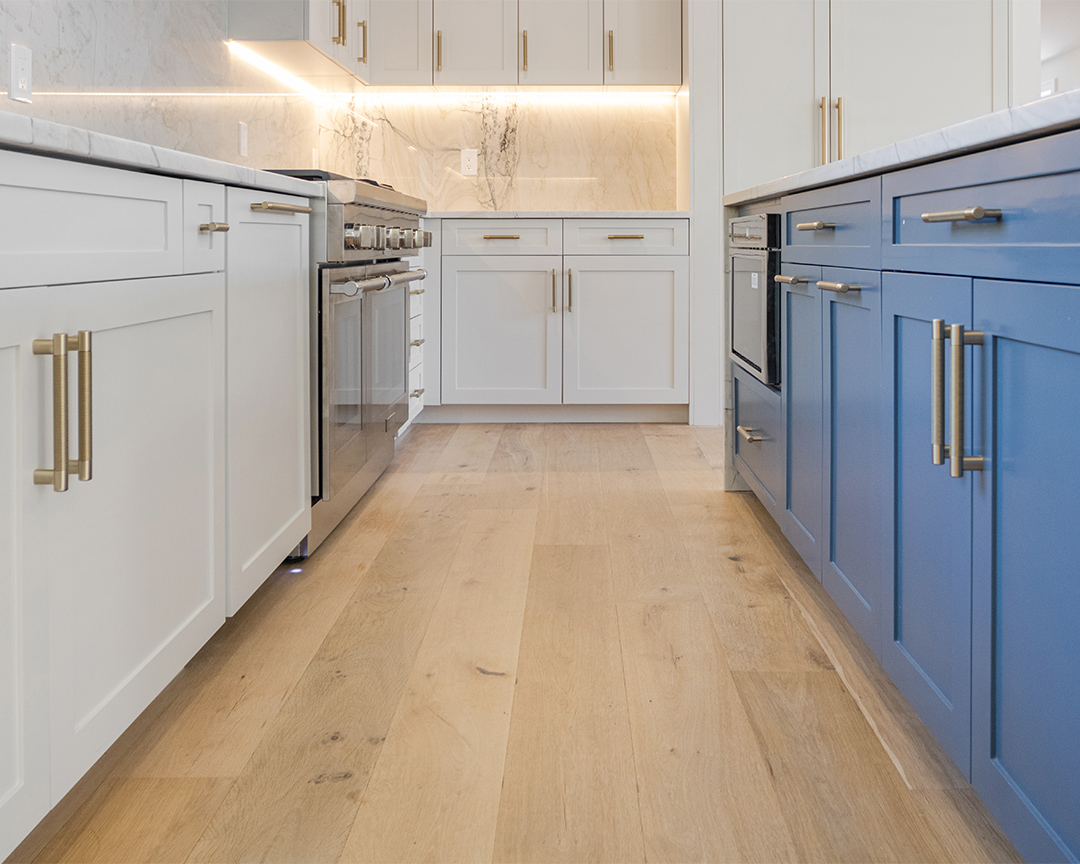 blue kitchen island marble backsplash white kitchen cabinets natural warm wide plank flooring