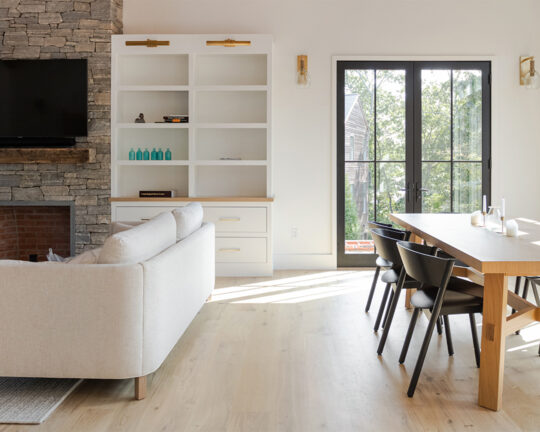 Sunny living and dining room with a fireplace, bookshelf, and light colored wood floor