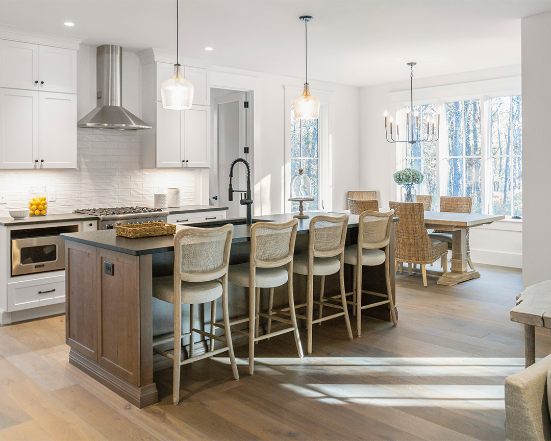 Sunny kitchen and island with stools with a dark colored wood floor.