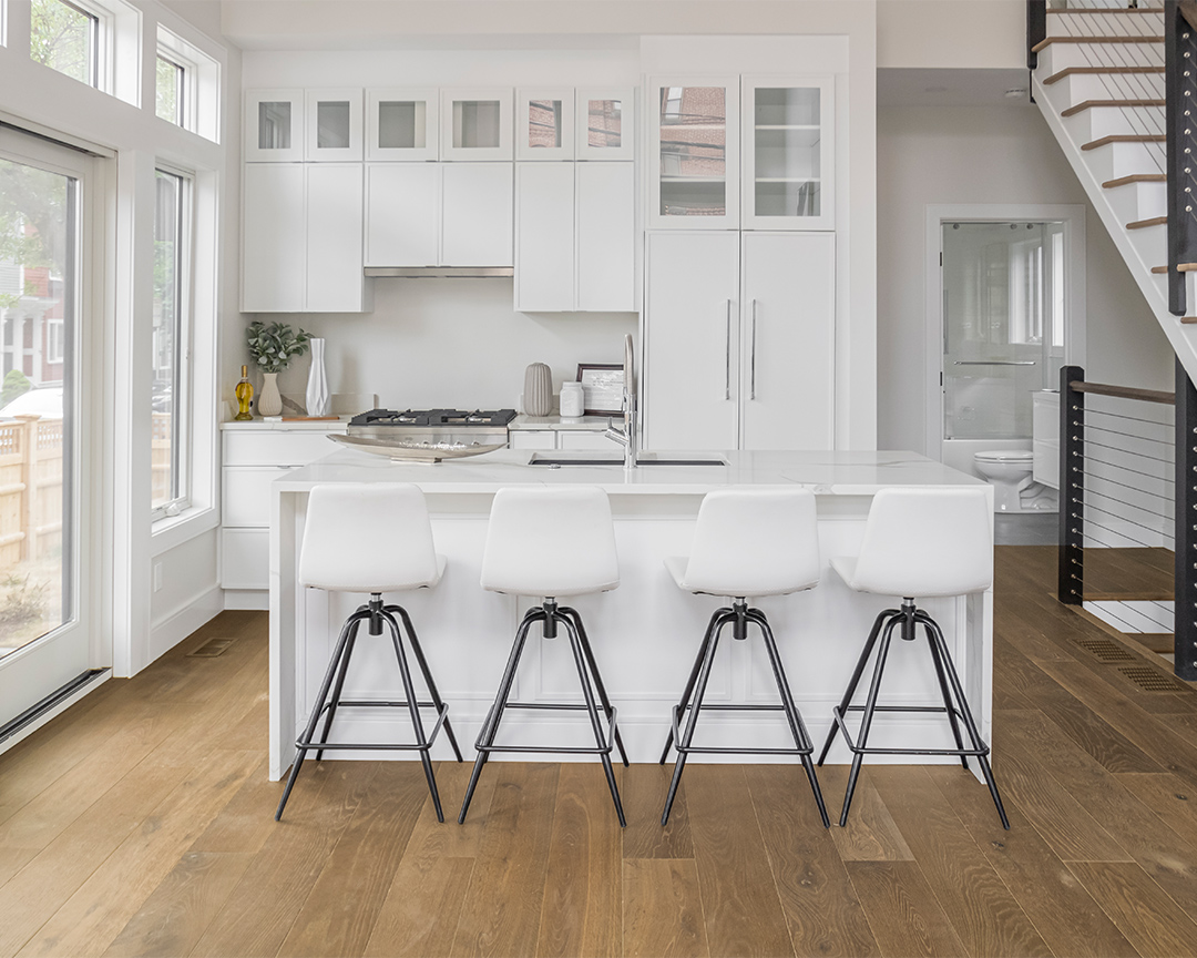 White colored kitchen chairs and cabinets with dark colored wood flooring.