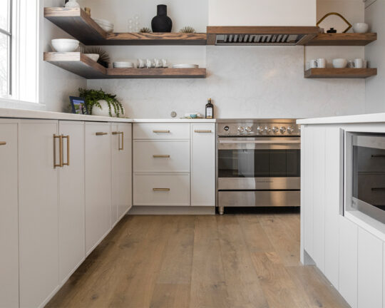 Close up of a wood floor in a modern kitchen with white cabinets and brown accents