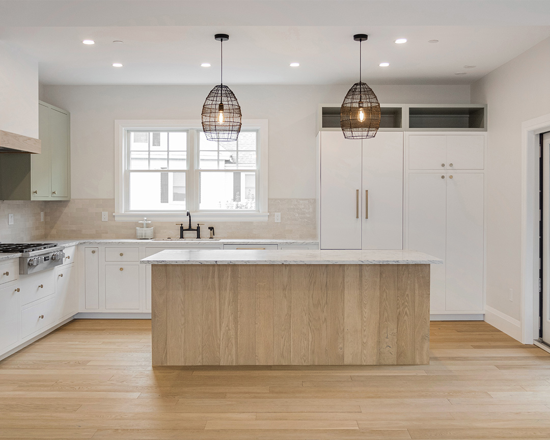 Modern, open kitchen design with white cabinets, wood paneled island and brightly colored hardwood flooring