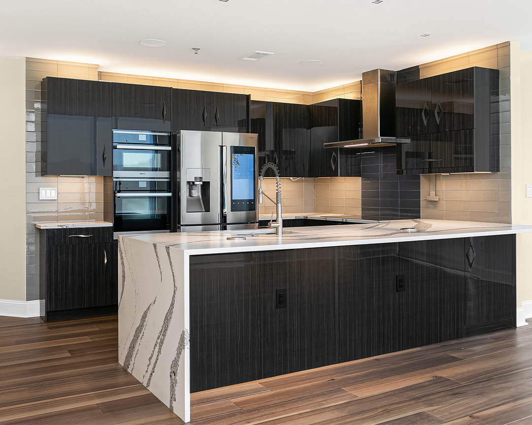 Modern kitchen with black cabinets and white countertops with a clean, linear wood floor