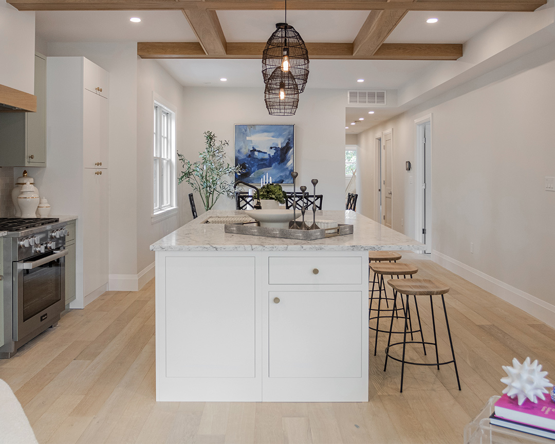 Lively kitchen design and island decorated with a painting, floral accents, and a light colored matte finish wood floor