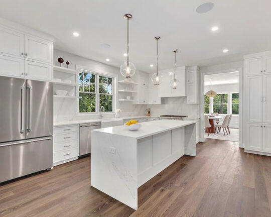 White kitchen with dark brown flooring.