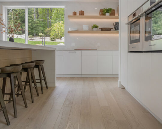 kitchen island and white cabinets with marble counters organic natural wide plank wood flooring