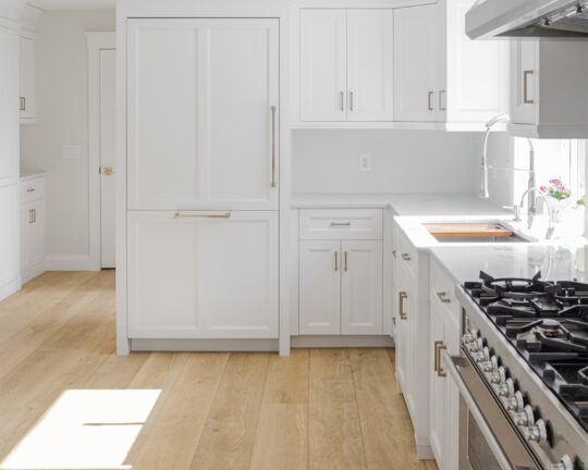 white clean modern kitchen design gold accents and natural looking wide plank flooring