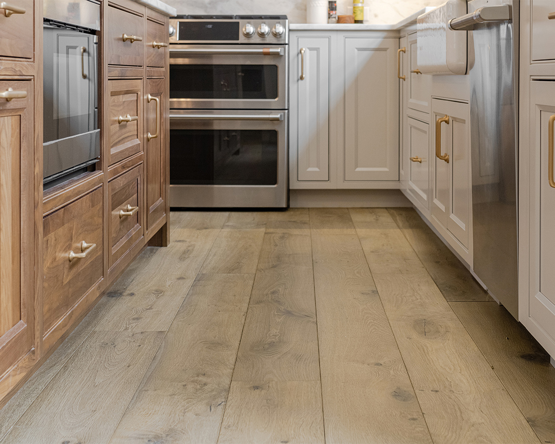 Close up of wood kitchen floor with white and brown cabinets