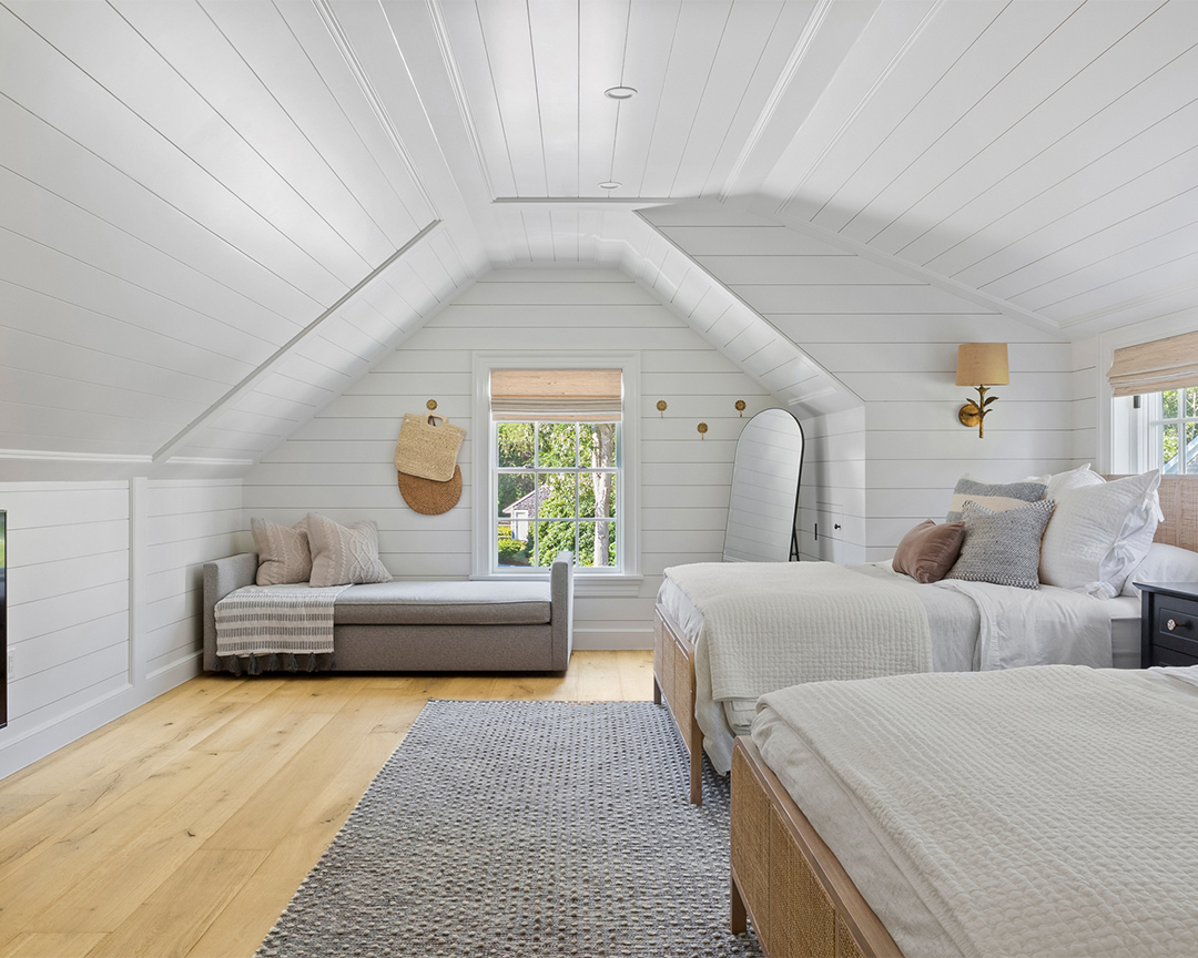 Coastal bedroom with white wall panels, gray carpet and light brown wood flooring