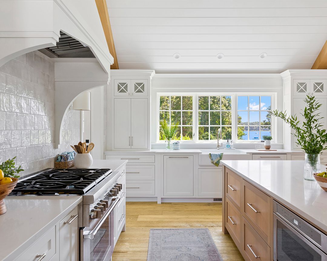 Coastal kitchen with ocean view, white cabinets, modern design and oak wood flooring