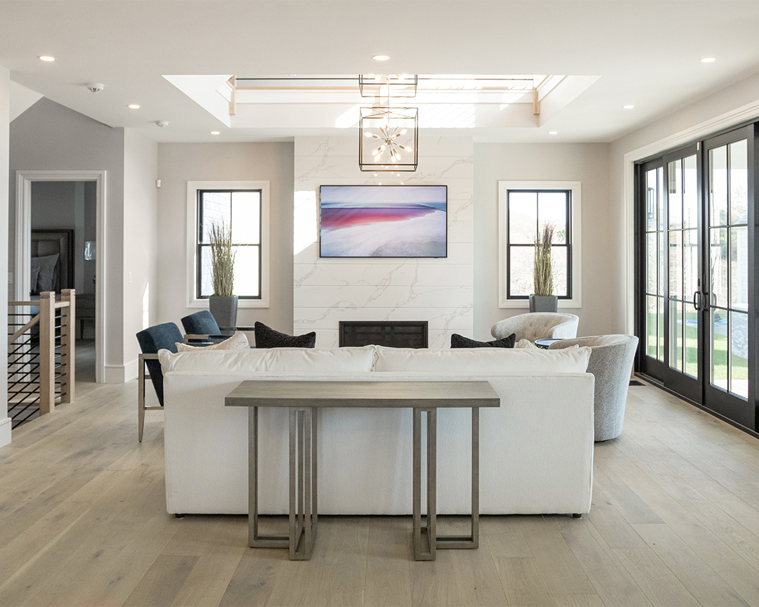 Bright, modern living room with neutral colors, abstract painting, decorative plants, and light wood floor