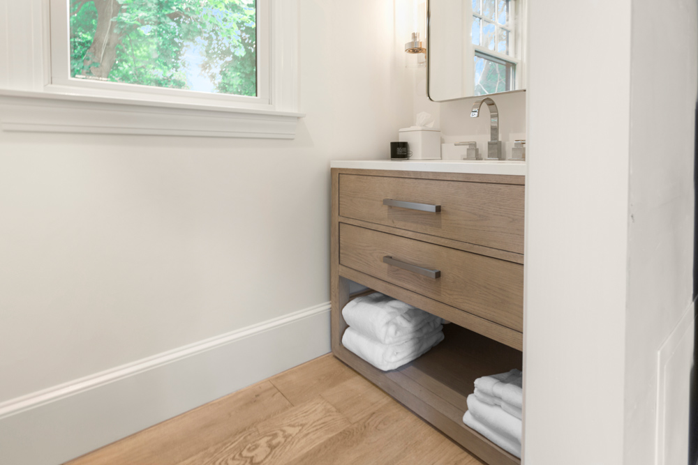 Bathroom sink with wooden cabinets and wood floor.