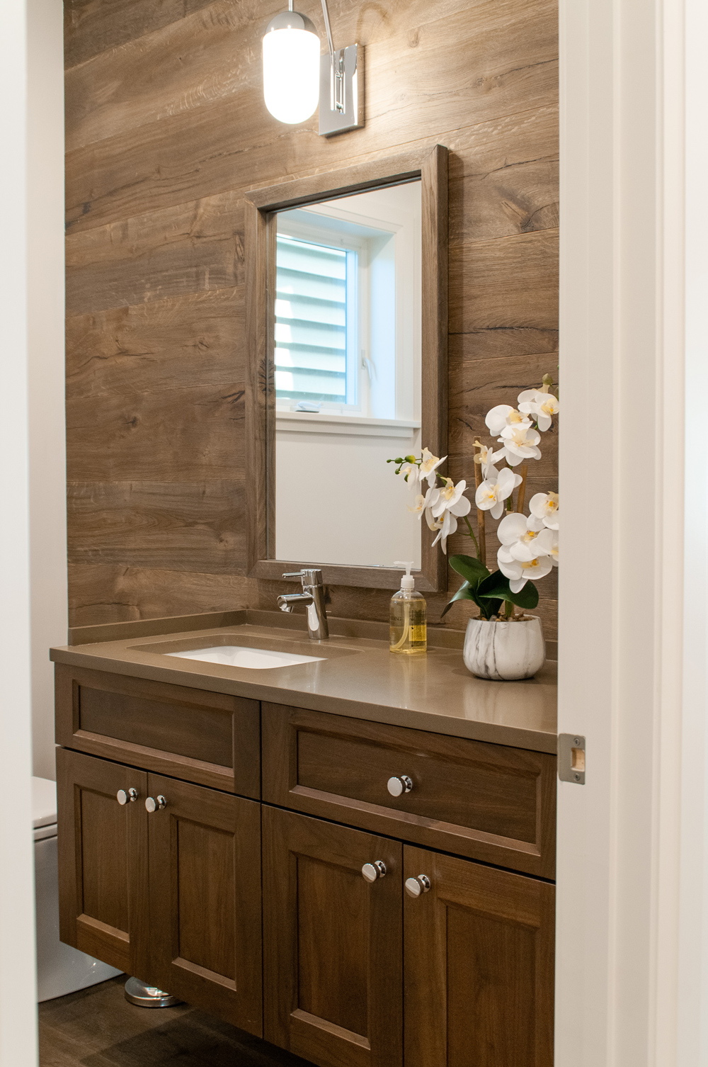 Mid century modern bathroom with wall paneling and wood cabinets.