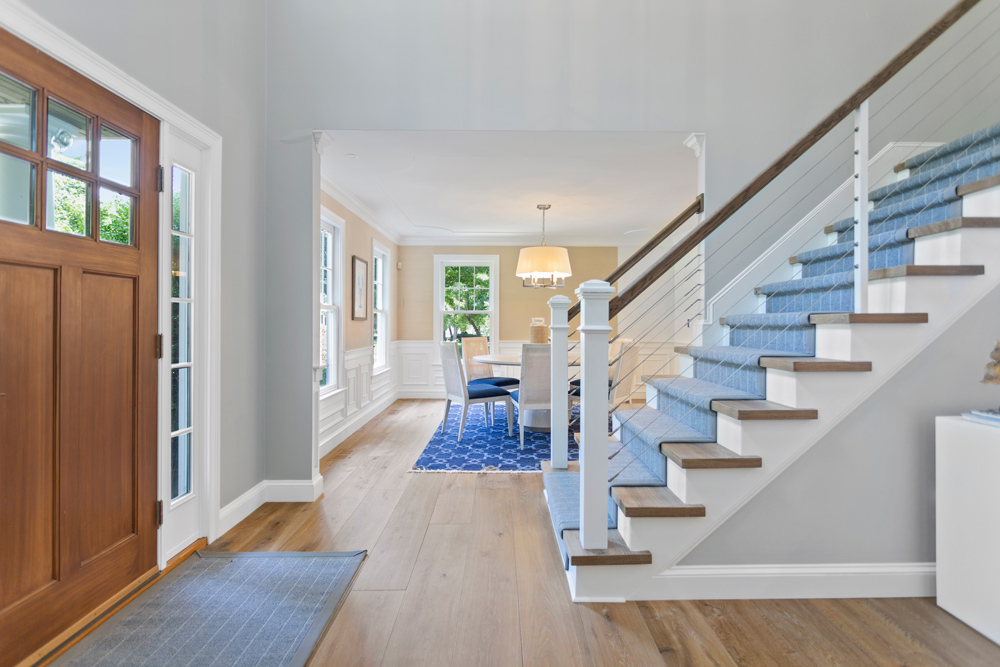 Blue carpeted staircase and entry door in a home with wood floor with tonal depth.