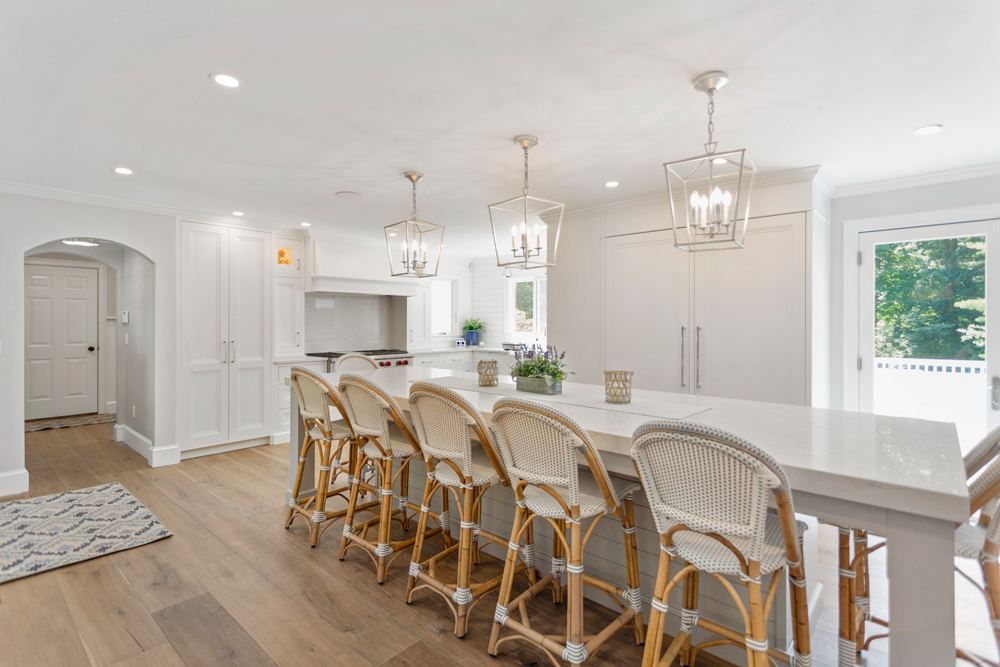 Kitchen with long island and a row of rattan chairs with artisan crafted wood flooring.