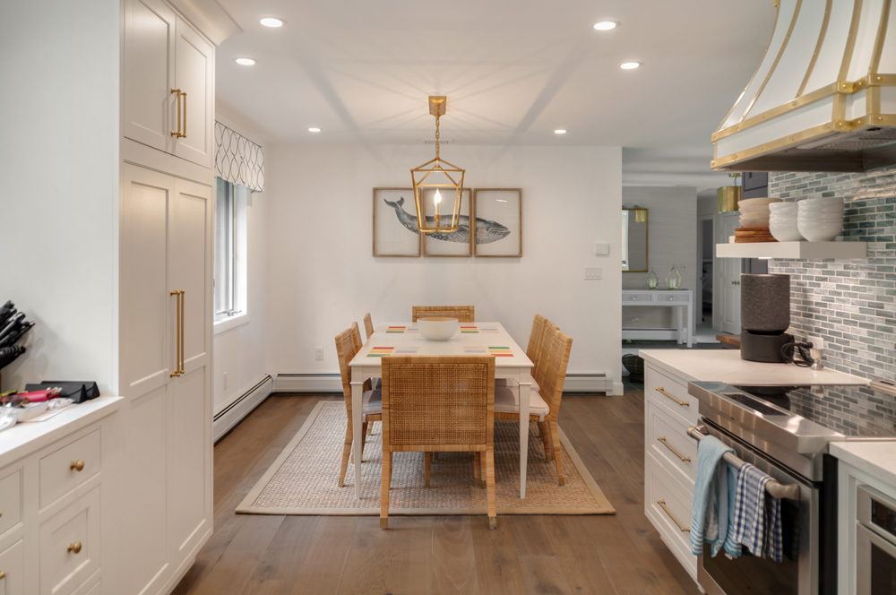 Kitchen and dining room with pendant light, gray backsplash, and engineered wood flooring.