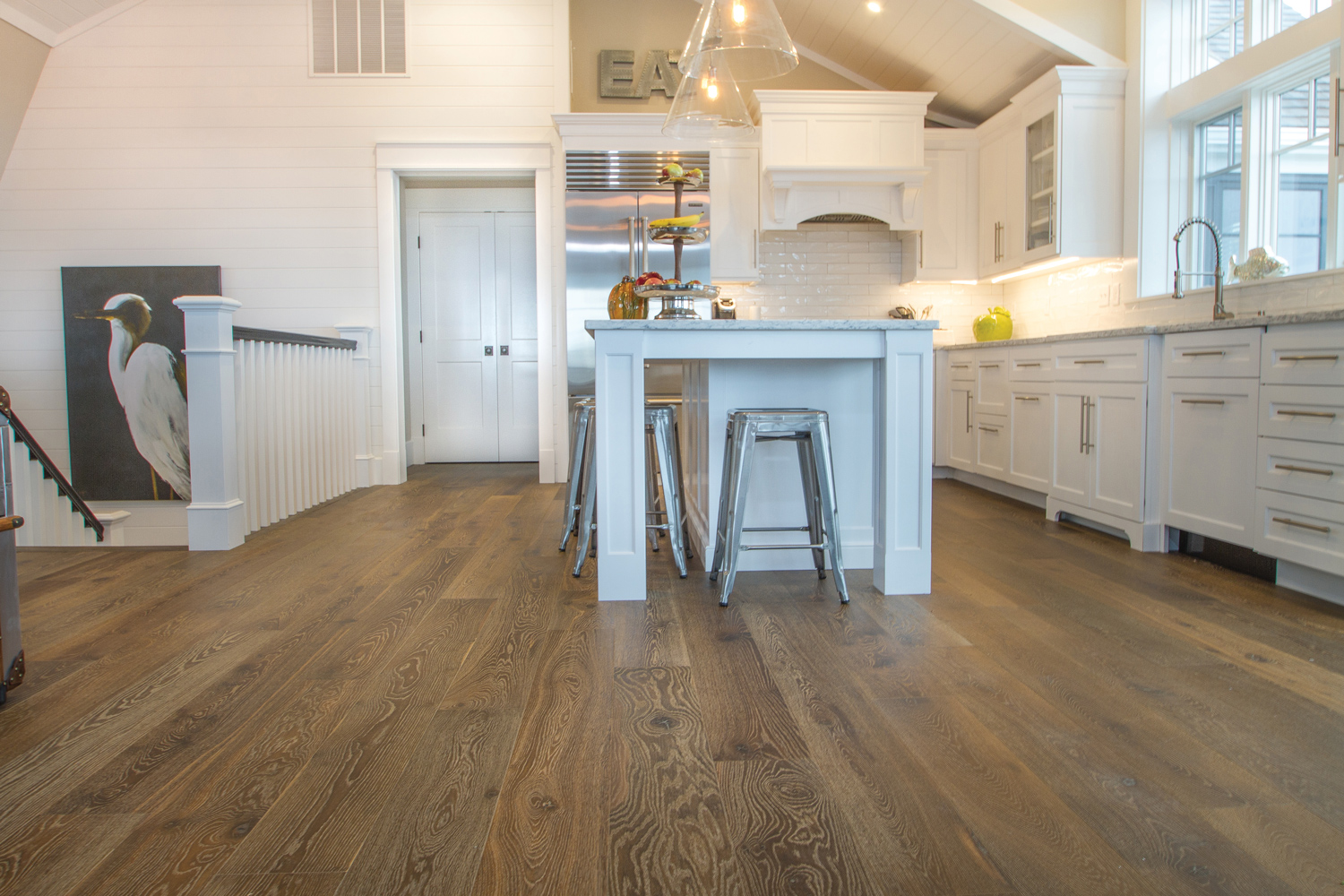 Clean kitchen design with white cabinets and island with silver accents and a deep espresso colored floor.