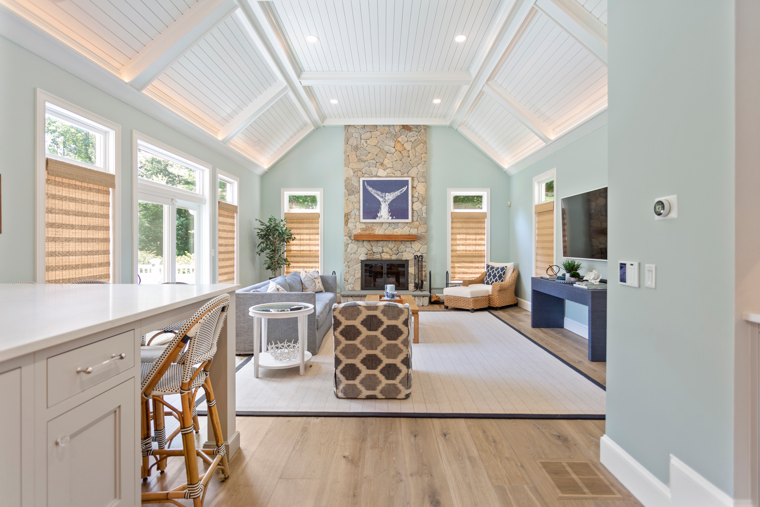Elegant beach house with living room and stone fireplace, large area rug, and artisan crafted hardwood flooring.