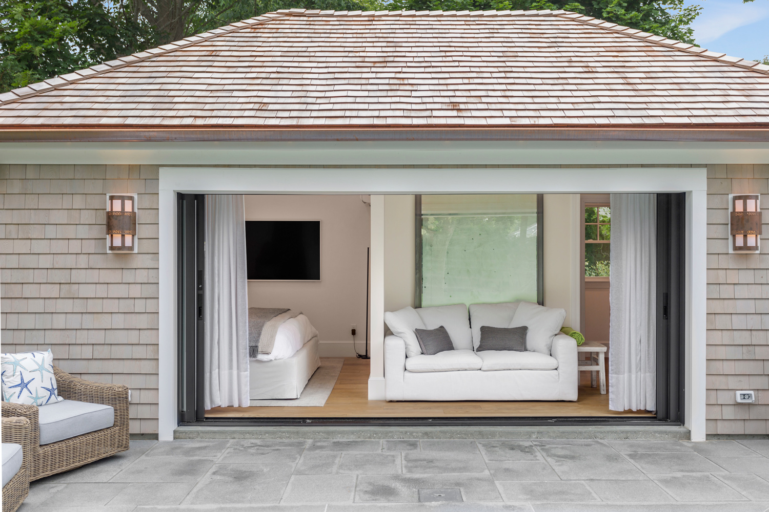 Luxury pool house with wood flooring and wide glass door.