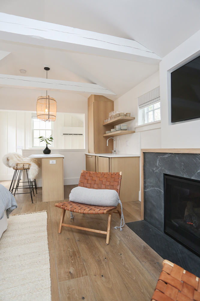 Modern boho studio with decorative chairs, fireplace, and small kitchen and dining nook.