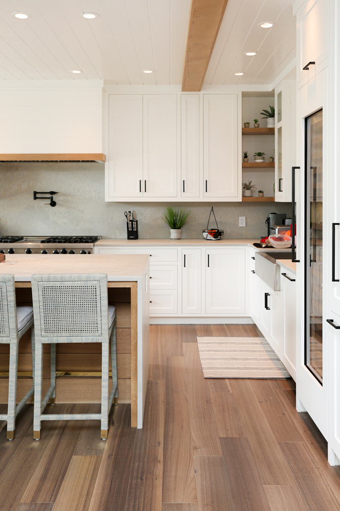 Modern kitchen design with white cabinets and sustainable wood flooring.