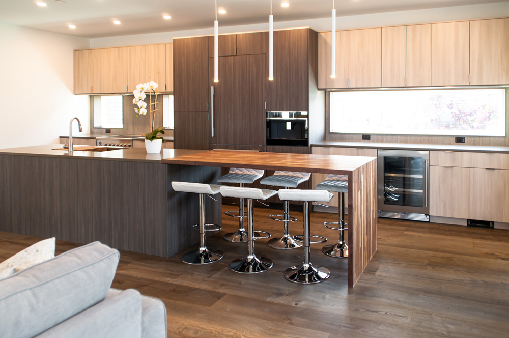 Modern kitchen with unique island and bar stools with a deep brown wood flooring.