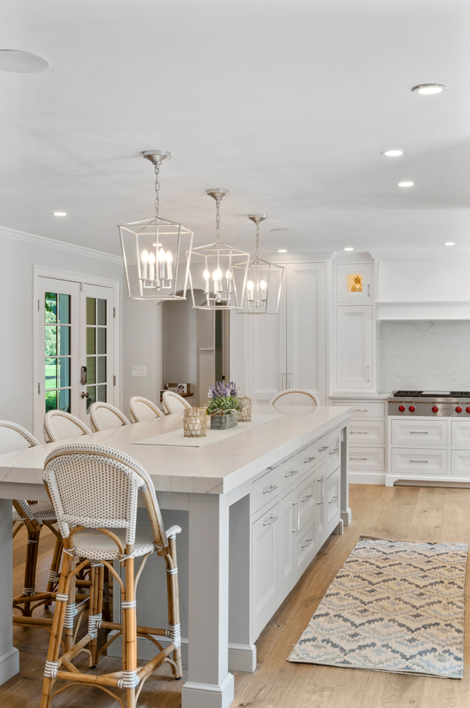 Modern kitchen design with island and rattan chairs with artisan crafted wood flooring.