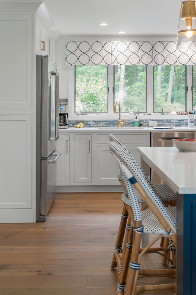 White modern kitchen design and rattan chairs at island with a wire brushed wood floor.