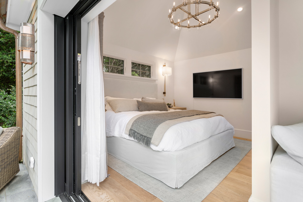 Cozy living room design with large open sliding door, decorative chandelier, and soft colored wood floor.