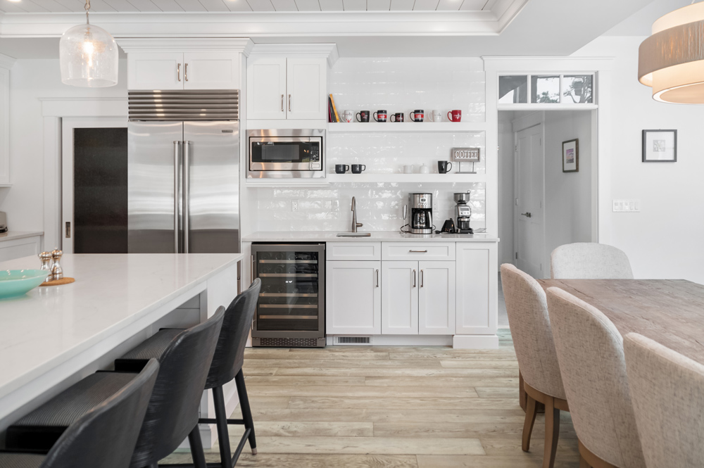 Kitchen with white cabinets and backsplash with dining table in view and a sustainable hardwood floor.