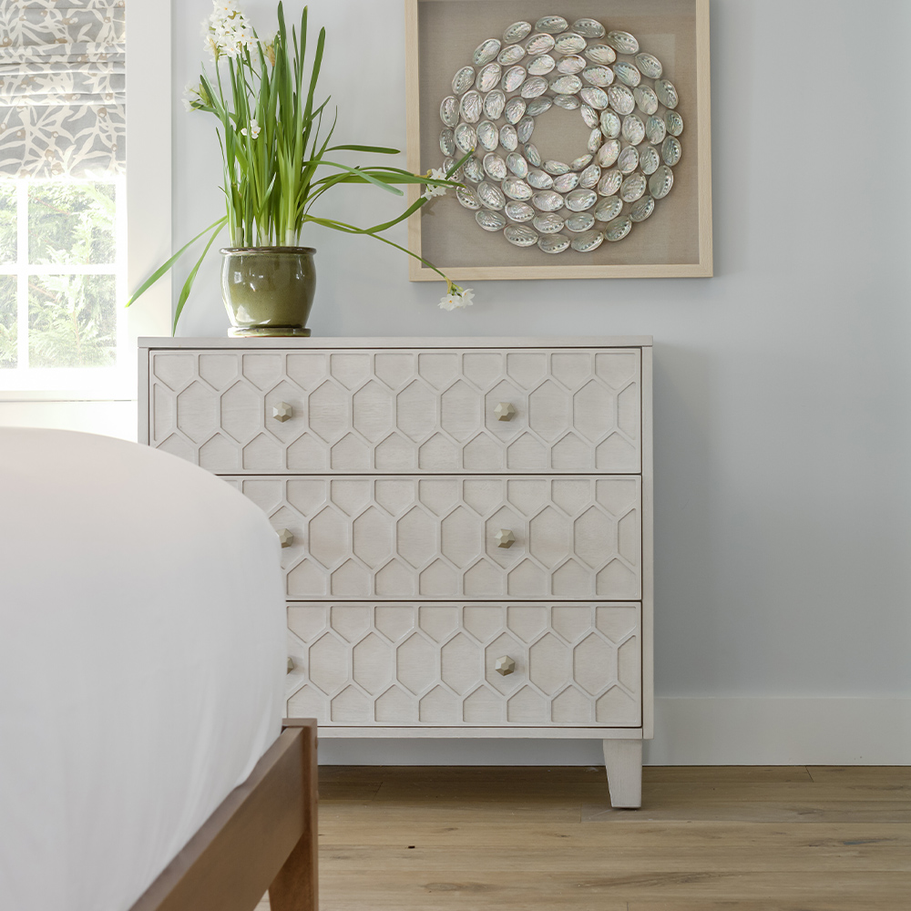 Bedroom dresser with plant and wall mounted painting.
