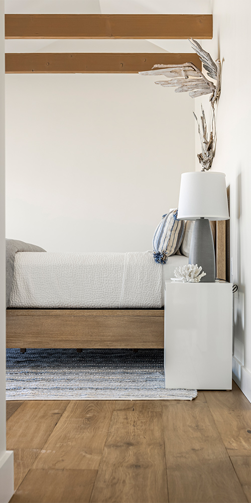 White bedroom with wooden accents and wide plank wood floor.