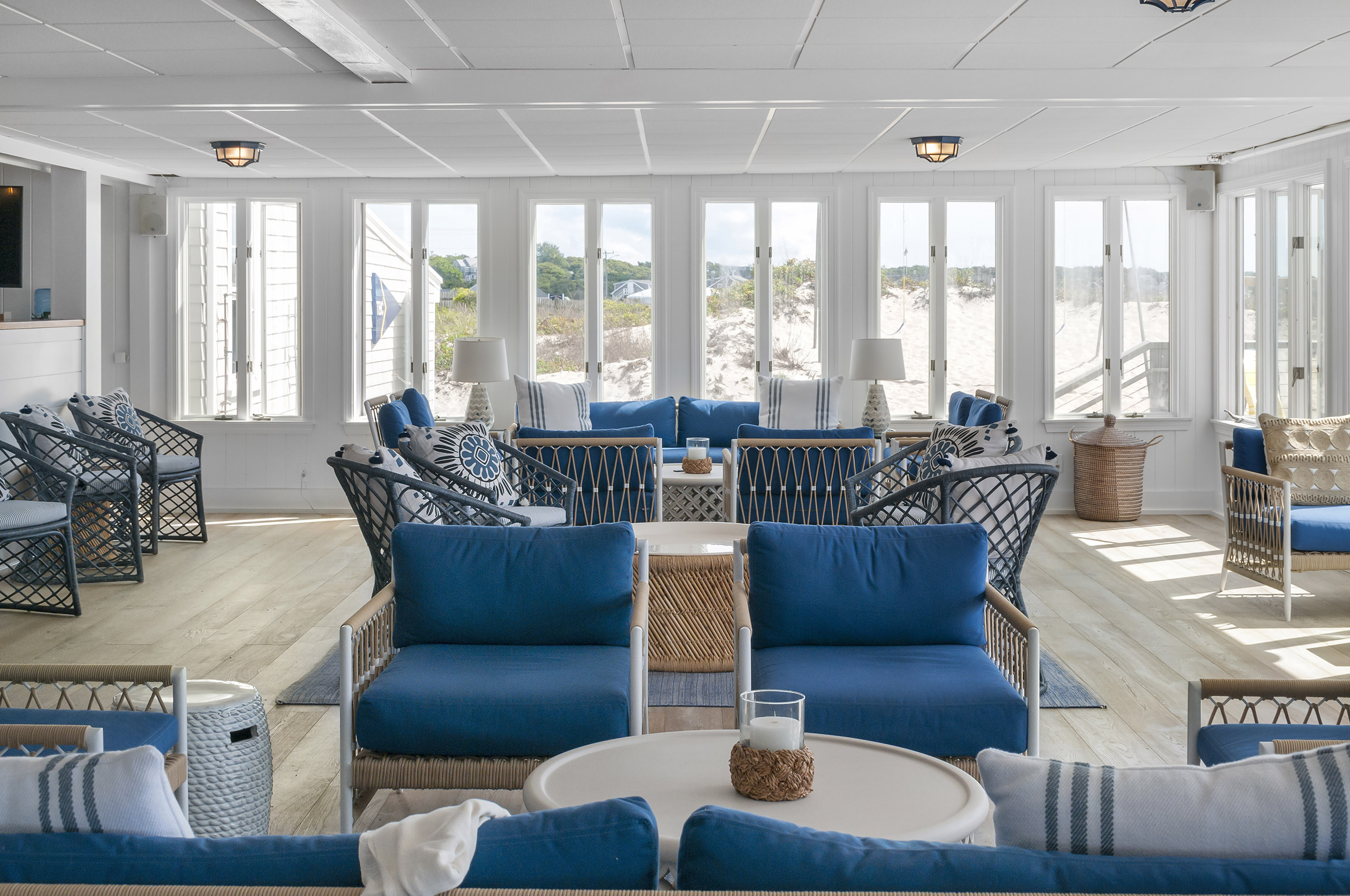 Large lounge with multiple sitting areas and sandy beach visible from windows.