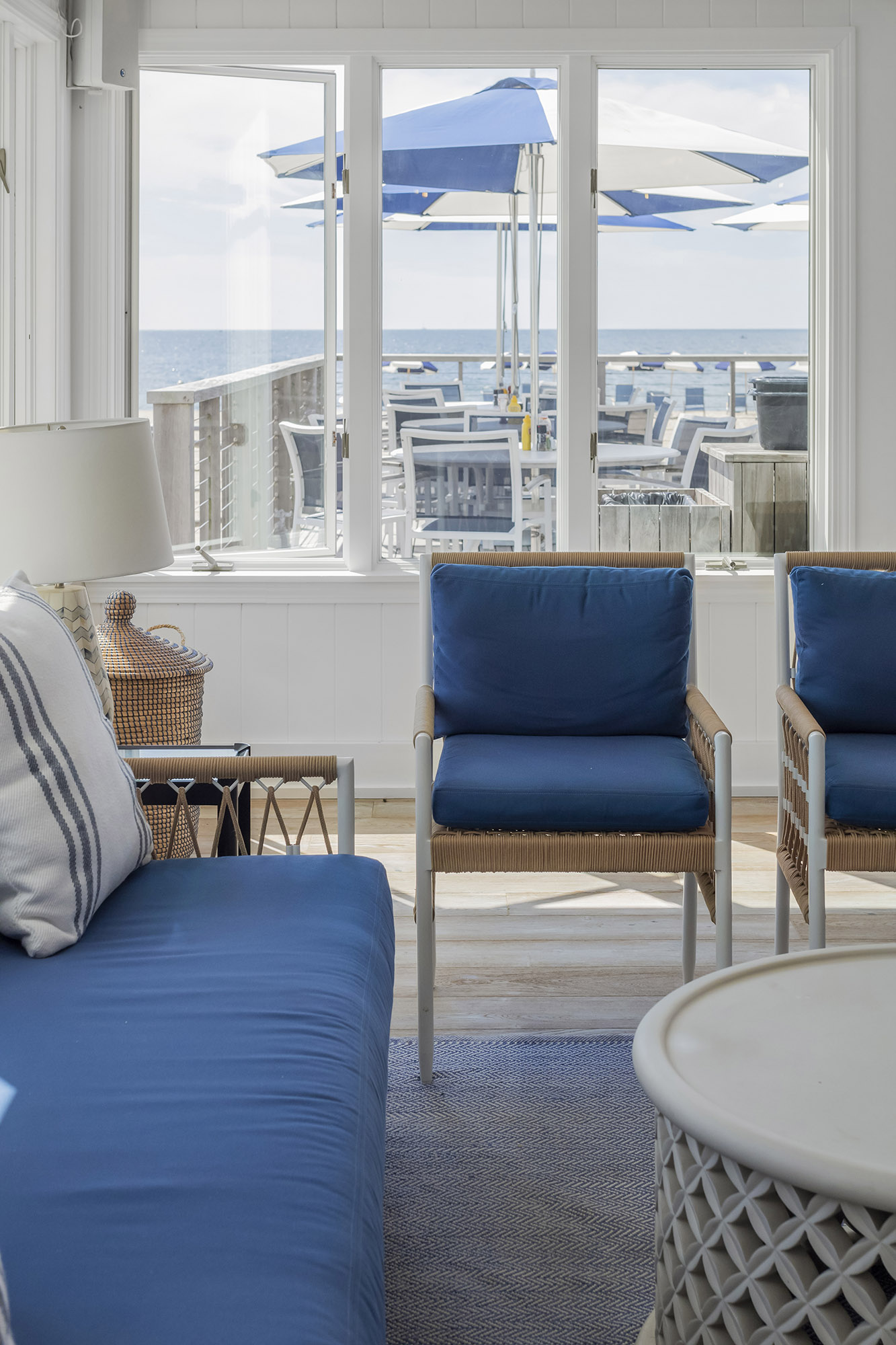 Beachfront sitting room with ocean and deck area visible from window.