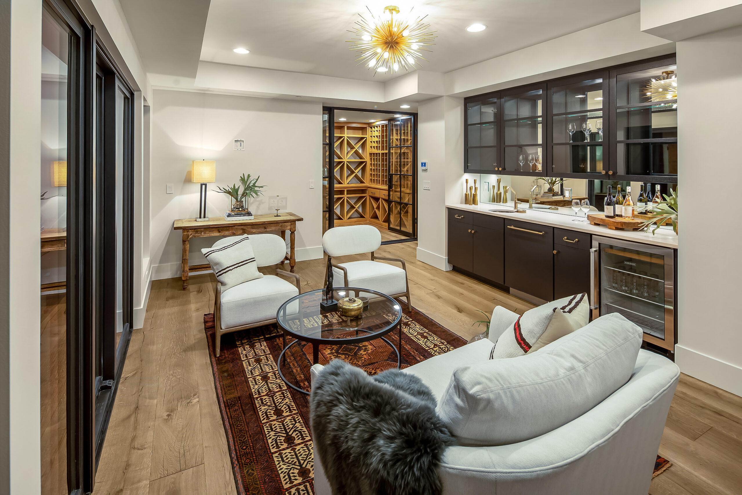 Heavily decorated living room space with bar, wine cellar, and wide plank wood floor.