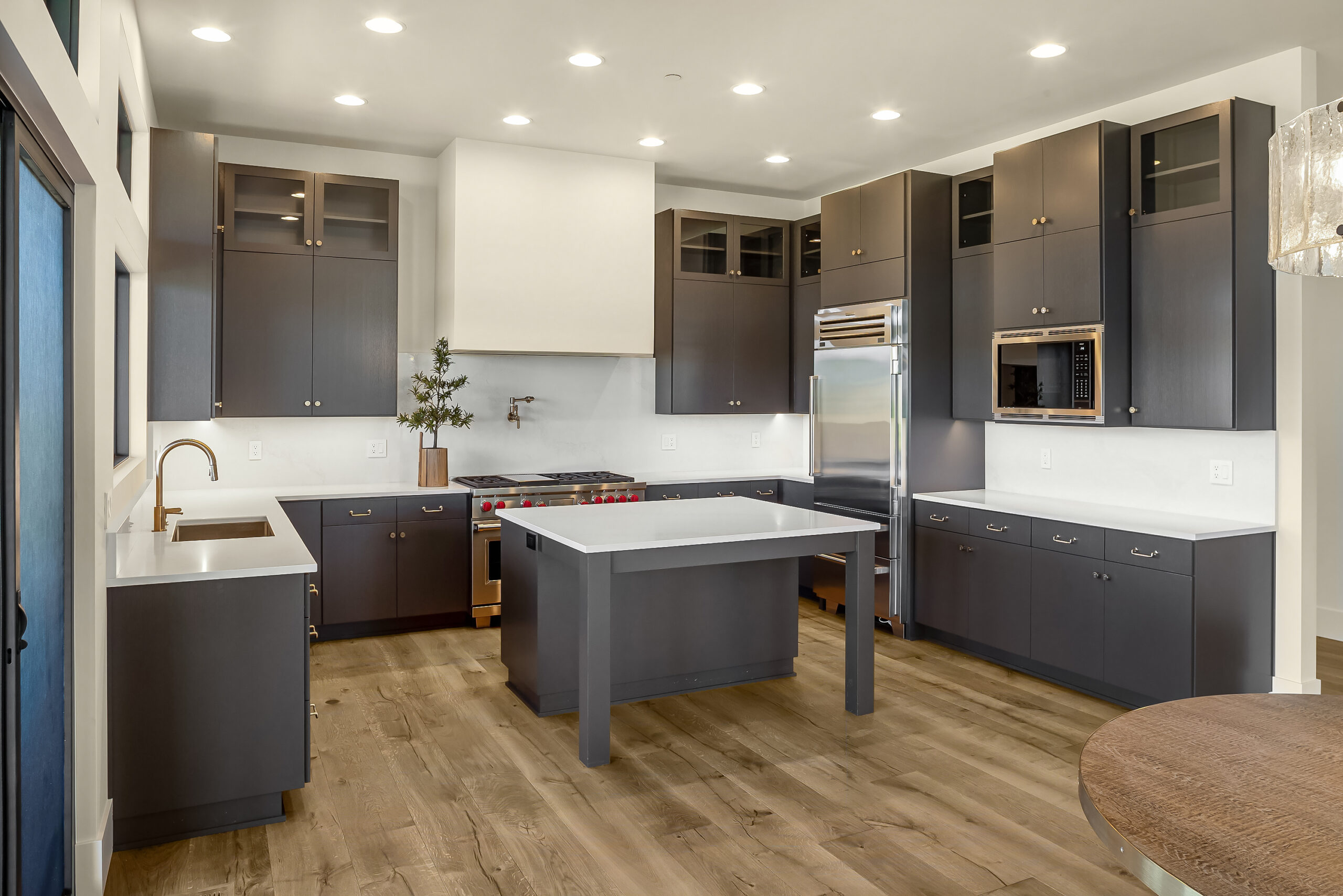 Uniquely designed kitchen with gray cabinets and a wide plank wood floor.