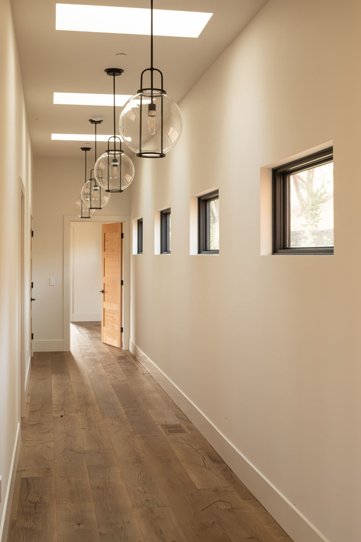 Hallway with unique hanging lights and rustic wood flooring.