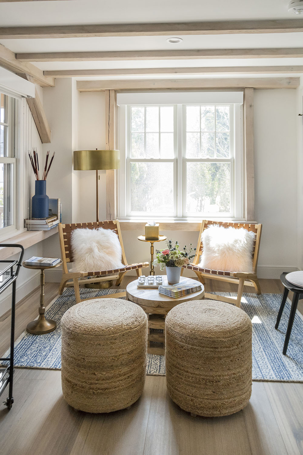 Sitting area at sunny commercial property with chairs, stools, carpet, and wood floor