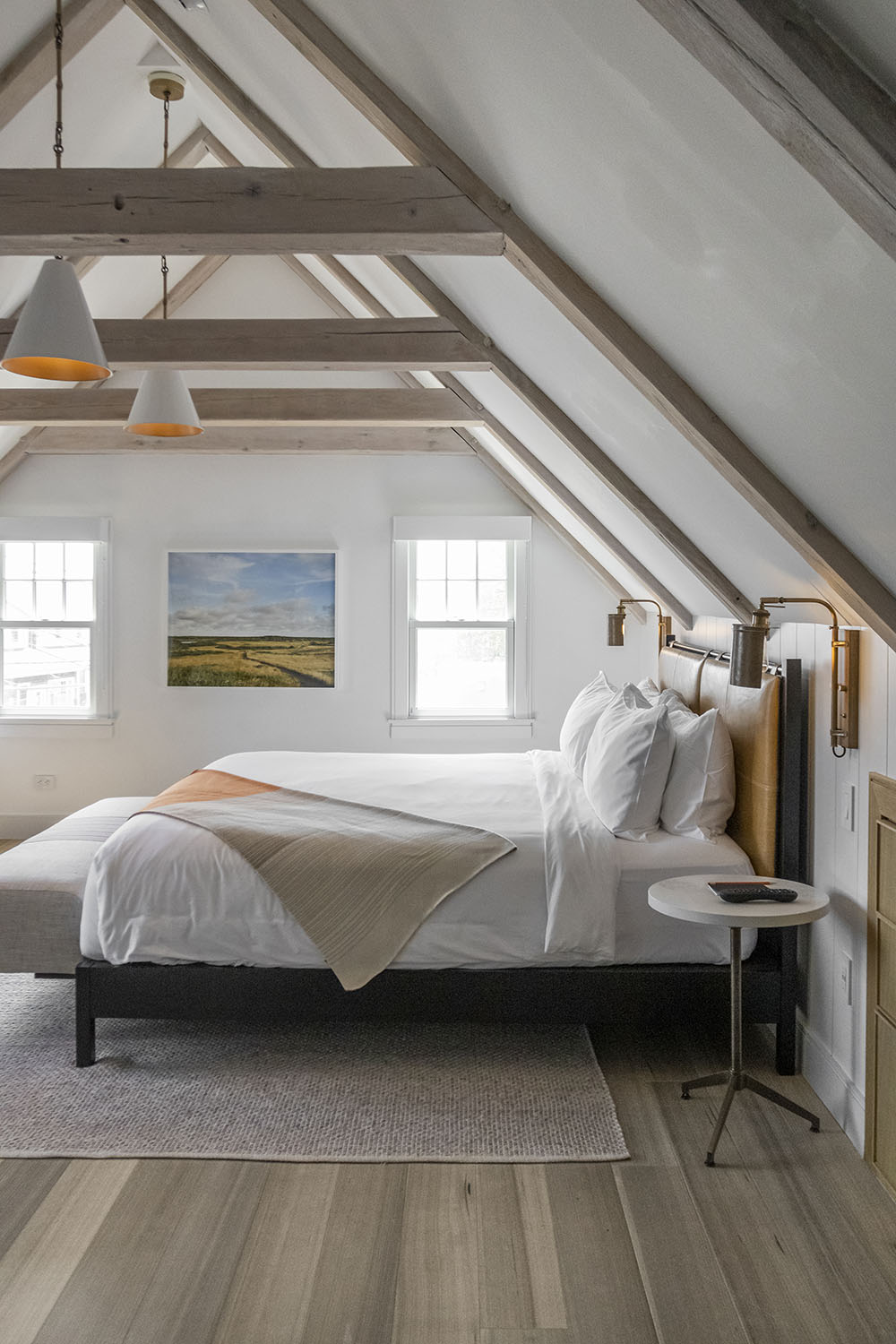 Beach bedroom with landscape painting, area rug, and wood flooring.