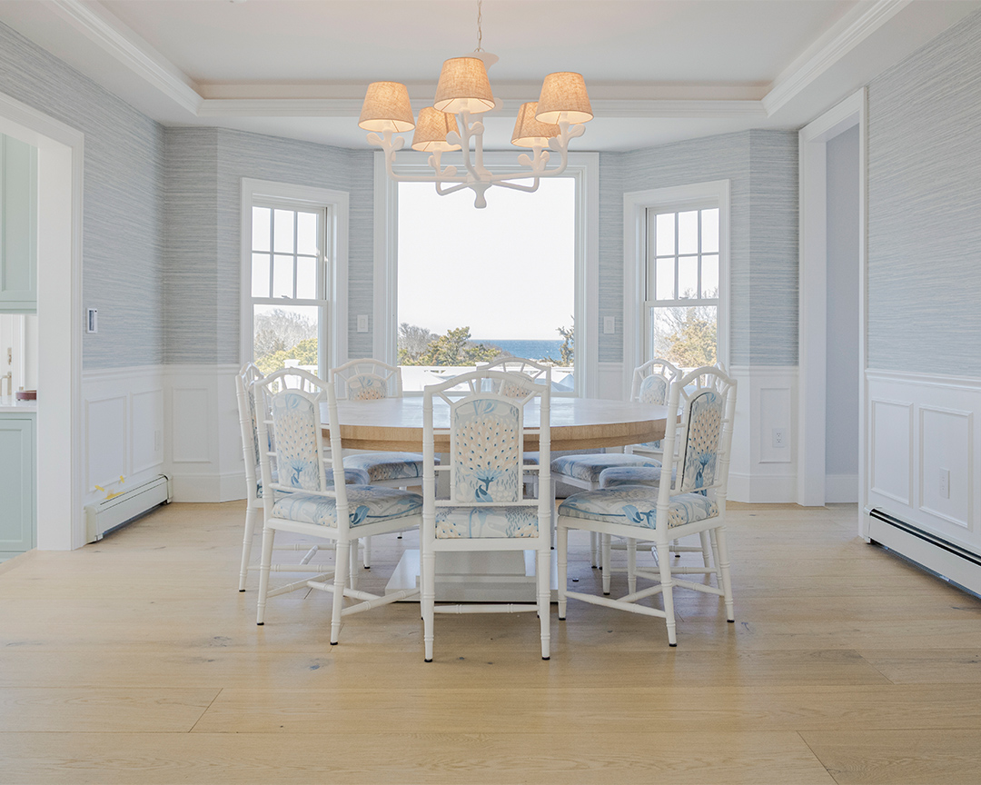 coastal dining room with a water view and blue and white pattered chairs and light wide plank wood flooring
